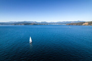 Sailboat near coastline, aerial drone footage, Vancouver Island, Sooke BC, sunny day ocean.