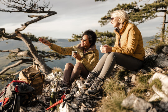 Women Enjoying Tea While Hiking On Mountain