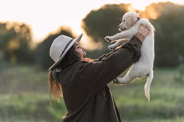 Fotobehang Mujer joven con cachorro de golden retriver posando feliz al atardecer en el campo © MiguelAngelJunquera