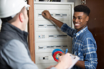 side view of male technician examining fusebox with multimeter probe