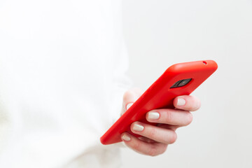 Close up of female hand using, holding smartphone in red phone case on white background. Copy space.
