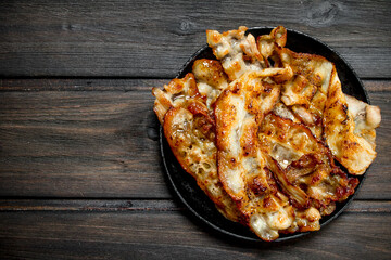 Fried bacon in a pan with spices.