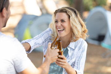 girl with boyfriend having fun drinking a beer in camping