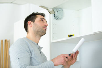 Naklejka na ściany i meble a worker installing kitchen cupboard