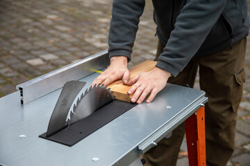 Brett mit beiden Händen festhalten und mit Kreissäge klein sägen