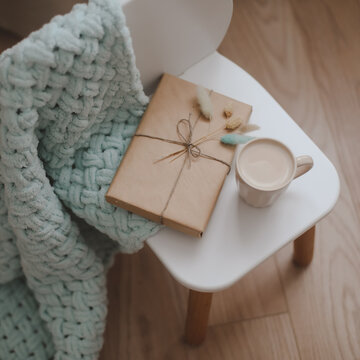 Composition with a gift, book, cup of coffee and plaid top view