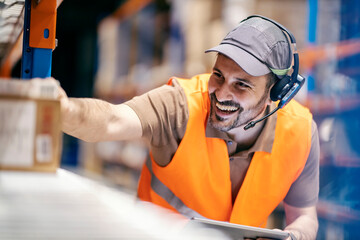 Smiling warehouse supervisor with working gadgets is checking on goods and doing logistics.