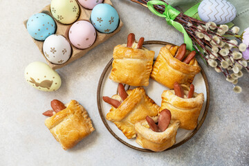 Buns in the form of an Easter rabbit from sausage and cheese in a yeast dough with colored eggs on...