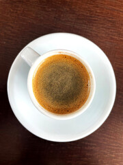 Brewed coffee in a white cup on a brown table