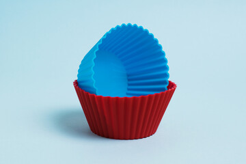 Red and blue silicone cupcake molds on a soft blue paper background