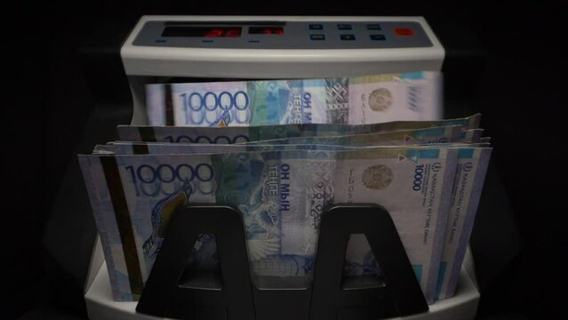 Closeup currency counting machine counting tenge bills. Money counting equipment for paper money calculation. Automatic mechanism for bank financial operations.