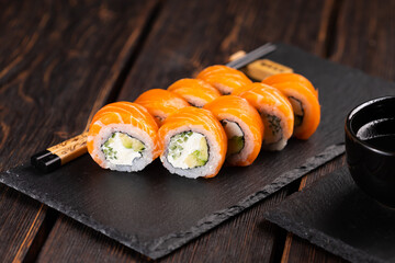 Sushi roll philadelphia with salmon and cucumber with avocado and cream cheese on black background. Sushi menu. Japanese food concept