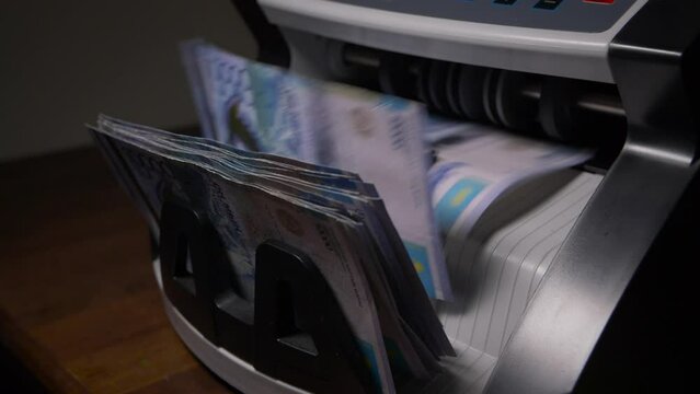 Closeup of currency counting machine counting tenge bills. Cash counting equipment. National currency of the Republic of Kazakhstan. 