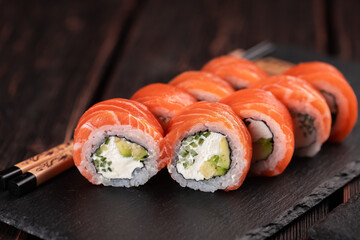 Sushi roll philadelphia with salmon and cucumber with avocado and cream cheese on black background. Sushi menu. Japanese food concept