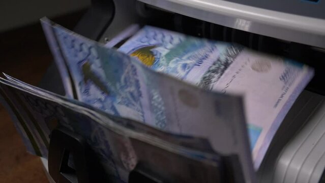 Closeup currency counting machine counting tenge bills. Cash counting equipment. National currency of the Republic of Kazakhstan. Very close-up in slow motion.