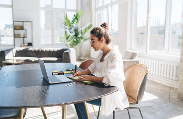 Woman writing in planner at home