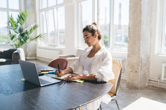 Focused woman writing in organizer with pen