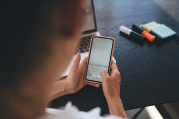 Crop anonymous person surfing internet on cellphone