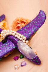 Purple children's plane lies among the flowers surrounded by beads and dramatic shadows. close up