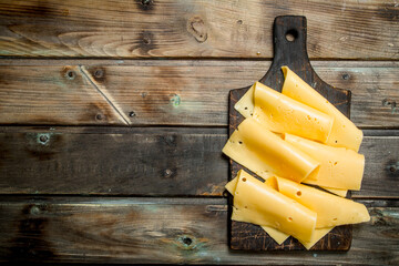 Thin slices of cheese on the cutting Board. - 561902402