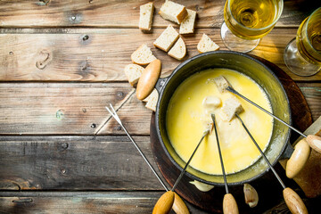 Delicious fondue cheese with bread slices and white wine.