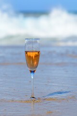 One glass of rose champagne or cava sparkling wine served on white sandy beach and blue ocean water, romantic vacation, winter sun on Fuerteventura, Canary, Spain