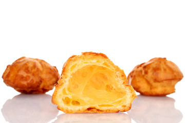 Half fresh chouquettes in focus, macro and two whole on a white background.