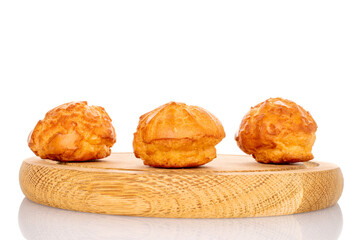 Three Chouquette on a round bamboo tray, close-up, on a white background.
