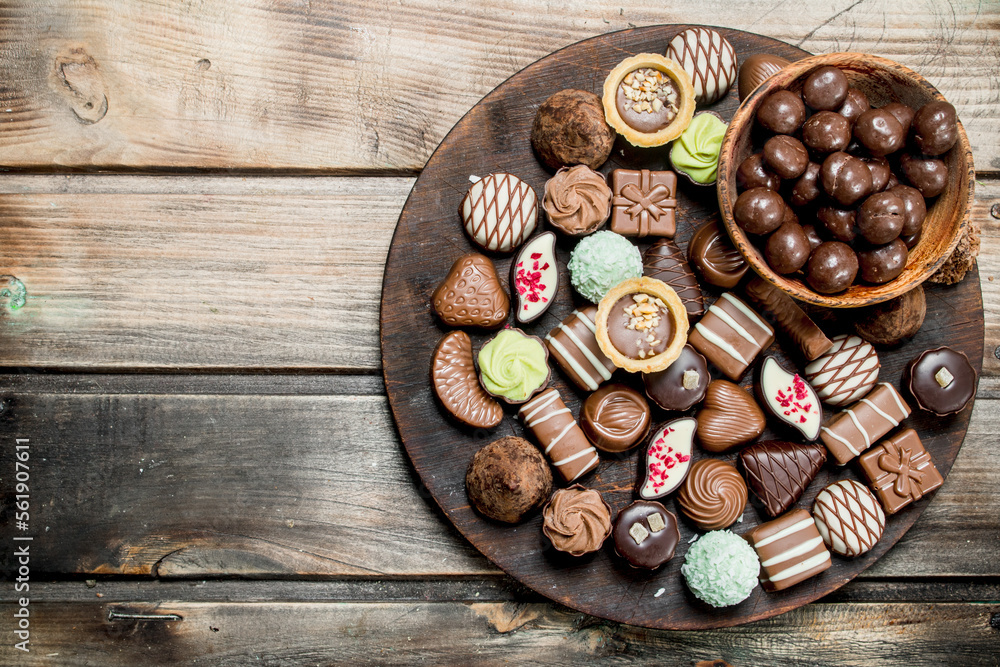 Wall mural Chocolate sweets on a wooden Board.