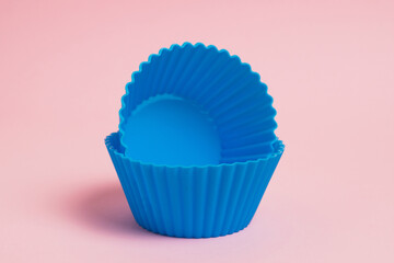 Blue silicone molds for cupcakes on a pink paper background