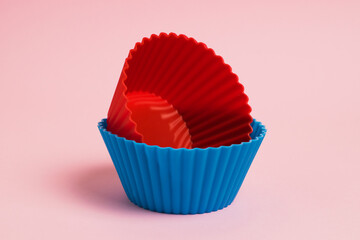 Red and blue silicone cupcake molds on a pink paper background
