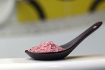 Crystal Himalayan pink salt in a ceramic spoon, on the edge of the bathroom