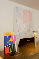 abstract painting on wall near reception desk with art book and computer monitor.