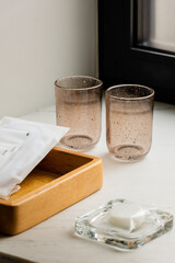clean glasses near wooden tray with sachets with wet wipes and soap.