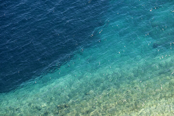 Azure water texture, transparent sea surface with a rocky bottom. Aerial view, natural turquoise background