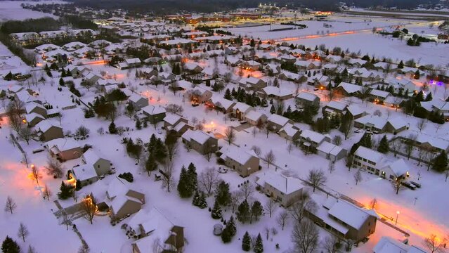 Aerial view of snow covered neighborhoods at night, illuminated by city lights.
