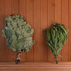 Two dry brooms on a shelf in the sauna. Birch and eucalyptus brooms for the steam room. Square Photo. Wellnes and Aromatherapy - obrazy, fototapety, plakaty