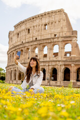 tourist girl taking a selfie with the roman colosseum in the background in rome