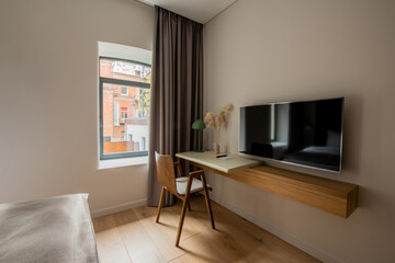 flat tv screen near wooden desk and chair in hotel room.
