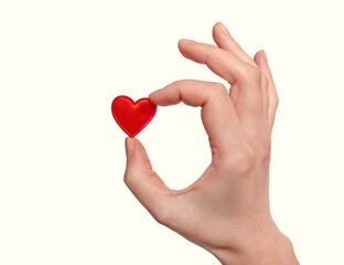 Obraz premium A woman's hand holds a small red heart with her fingers