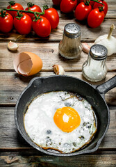 Fried egg in a pan with tomatoes.