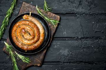 Fried sausages with branches of fragrant rosemary.