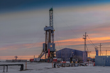 Fototapeta premium Drilling wells at an oil and gas field in the Arctic region. Production infrastructure and drilling rig. Beautiful winter sky. Polar Day