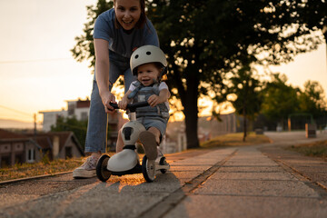Fototapeta premium Mother and daughter toddler play with children's kid's kick scooter
