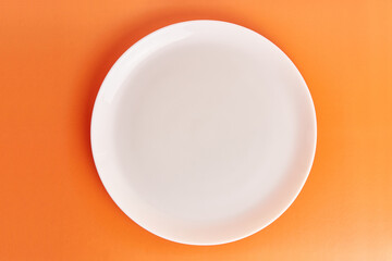 White plate on an orange background. Graphic background for designers.