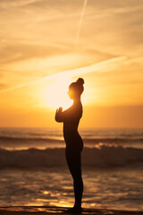 Fototapeta na wymiar Female meditating on beach at sundown