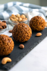 Homemade cereal bars made of oatmeal crumbs, cashew and almons nuts and caramel on black slate board. Easy recipe of homemade dessert without baking. Bliss balls for tea time.