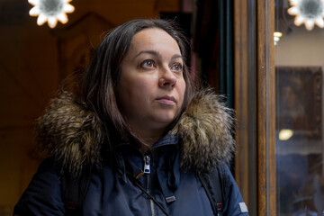 Street portrait of a 40-45-year-old woman looking at a night showcase, dark tone.