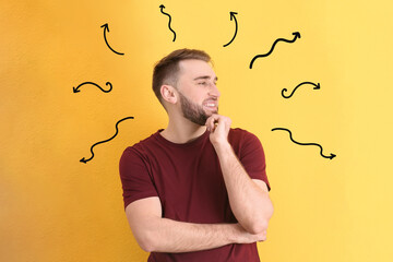 Choice in profession or other areas of life, concept. Making decision, young man surrounded by drawn arrows on yellow background