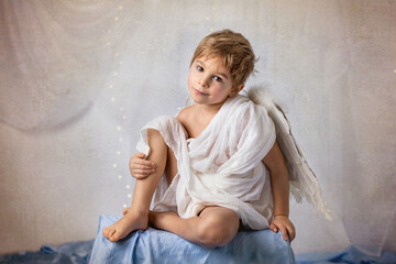 Little cupid toddle boy, holding bow and arrow, beautiful blond cherub
